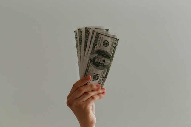Hand holding five $100 American bills