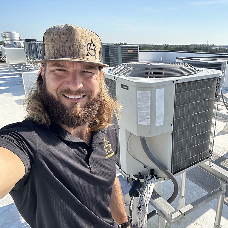 Jimmy Griffin, owner of A&G Air Condiditioning, smiling next to an HVAC system in Orlando, FL